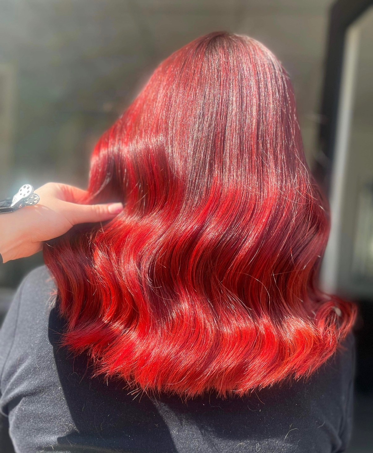 Bright red hair colour on wavy hair at ELM Hair and Beauty, Wrexham